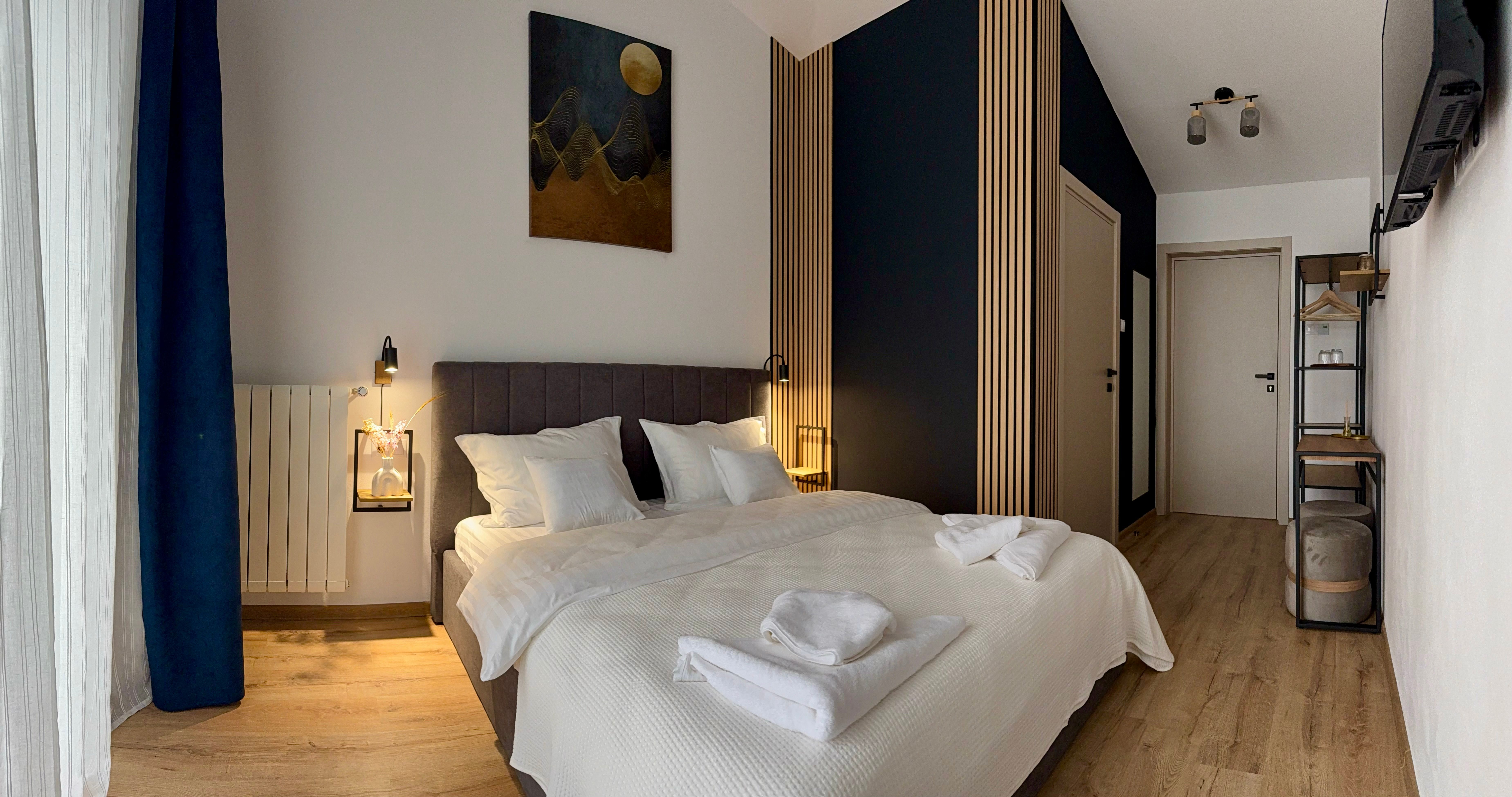 Modern hotel room with dark blue accents, wooden slat details, and warm lighting